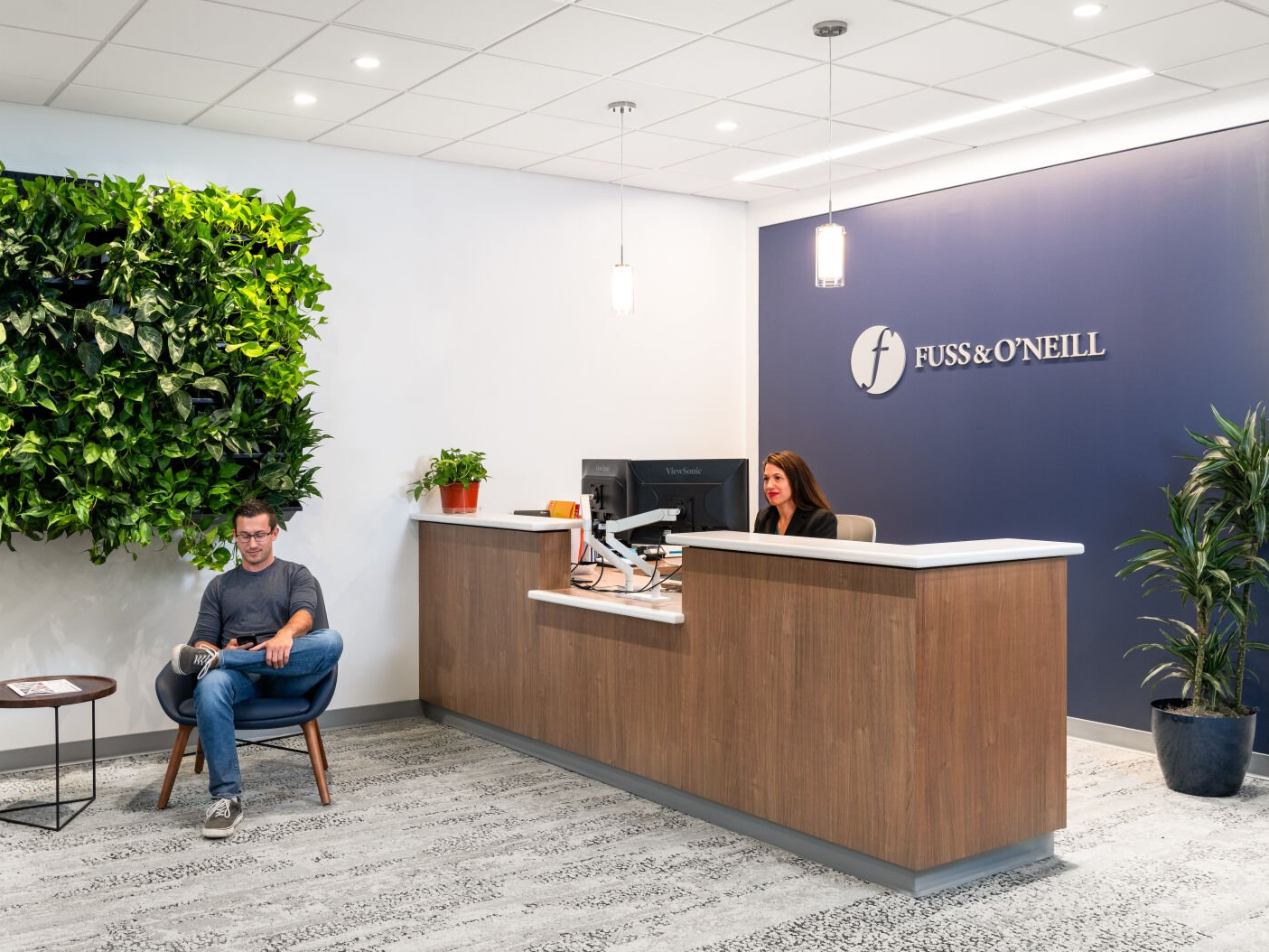 A man is sitting in a chair in front of a reception desk.