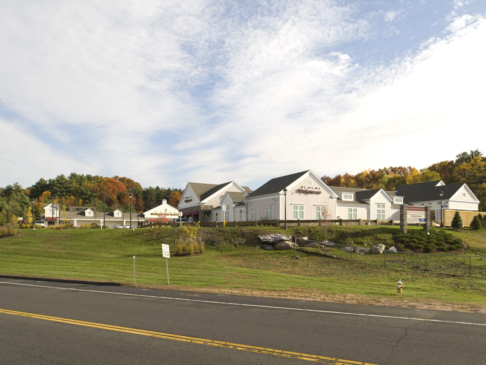 A row of white houses sit on a hill next to a road