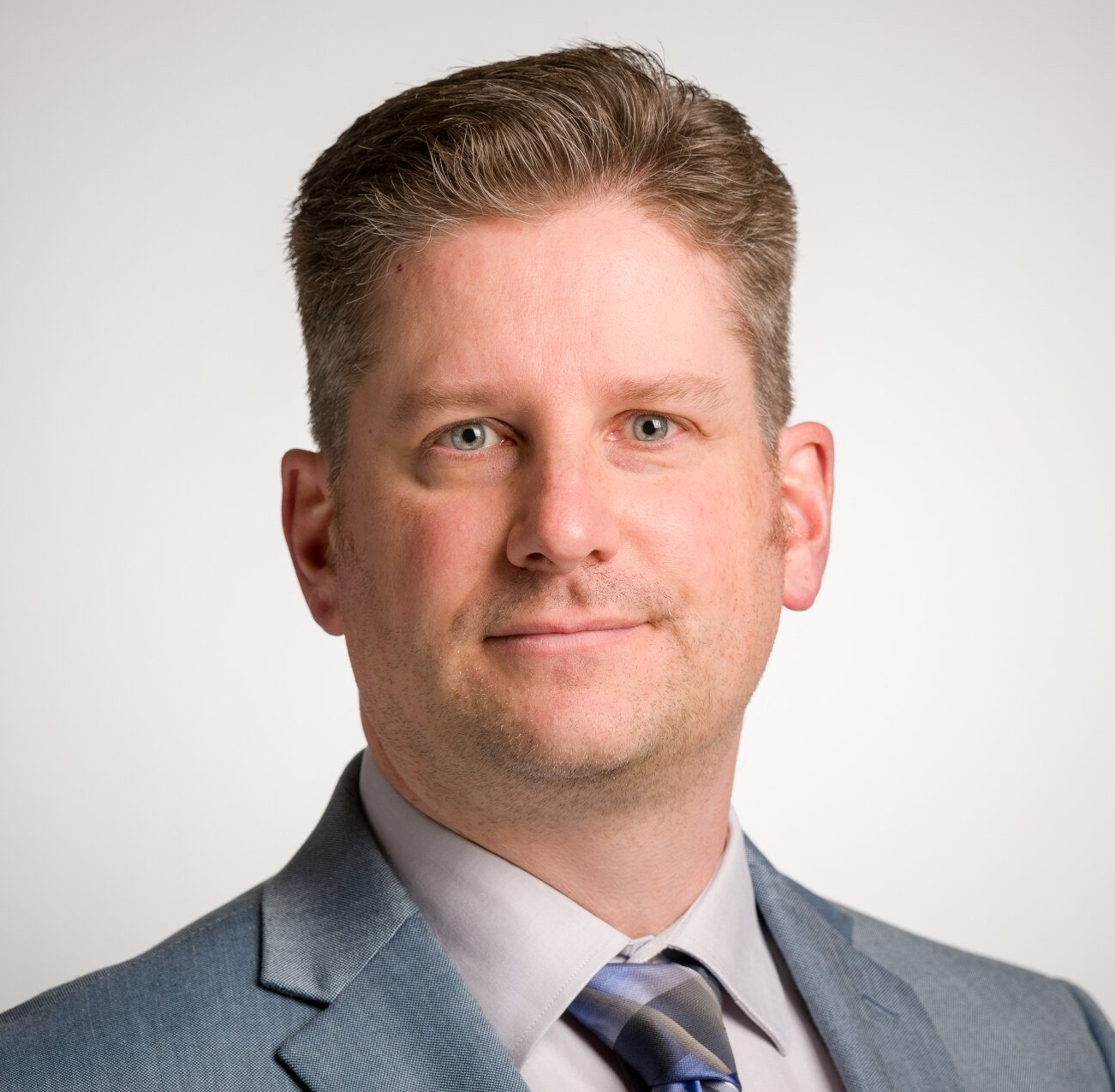 A man in a suit and tie is smiling for the camera.