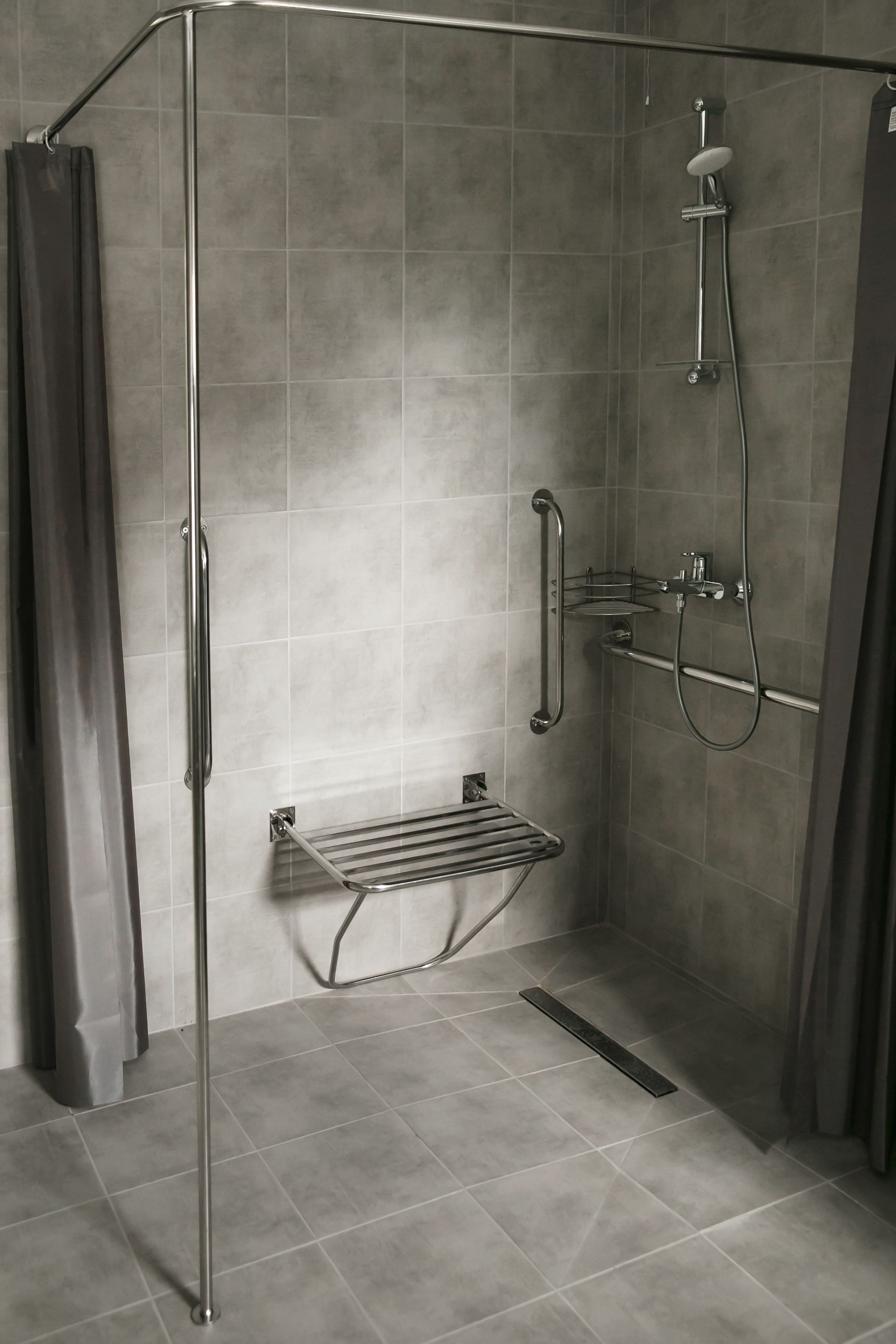 A black and white photo of a walk in shower with a bench.
