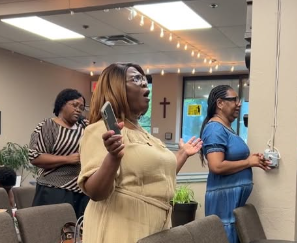 Minister praying with community members
