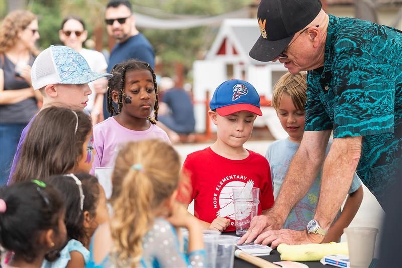 Man teaching children at an outdoor table during a hands-on activity