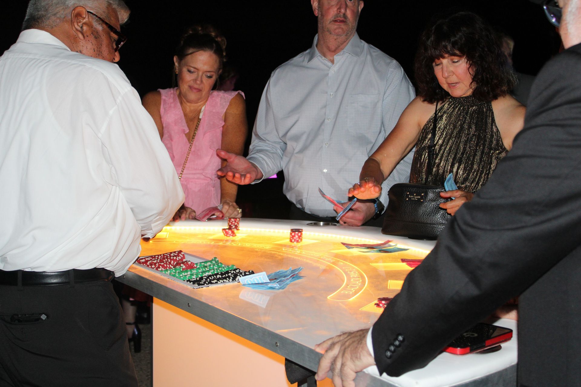 People gathered around a glowing interactive table, reaching toward bright lights in a dim room