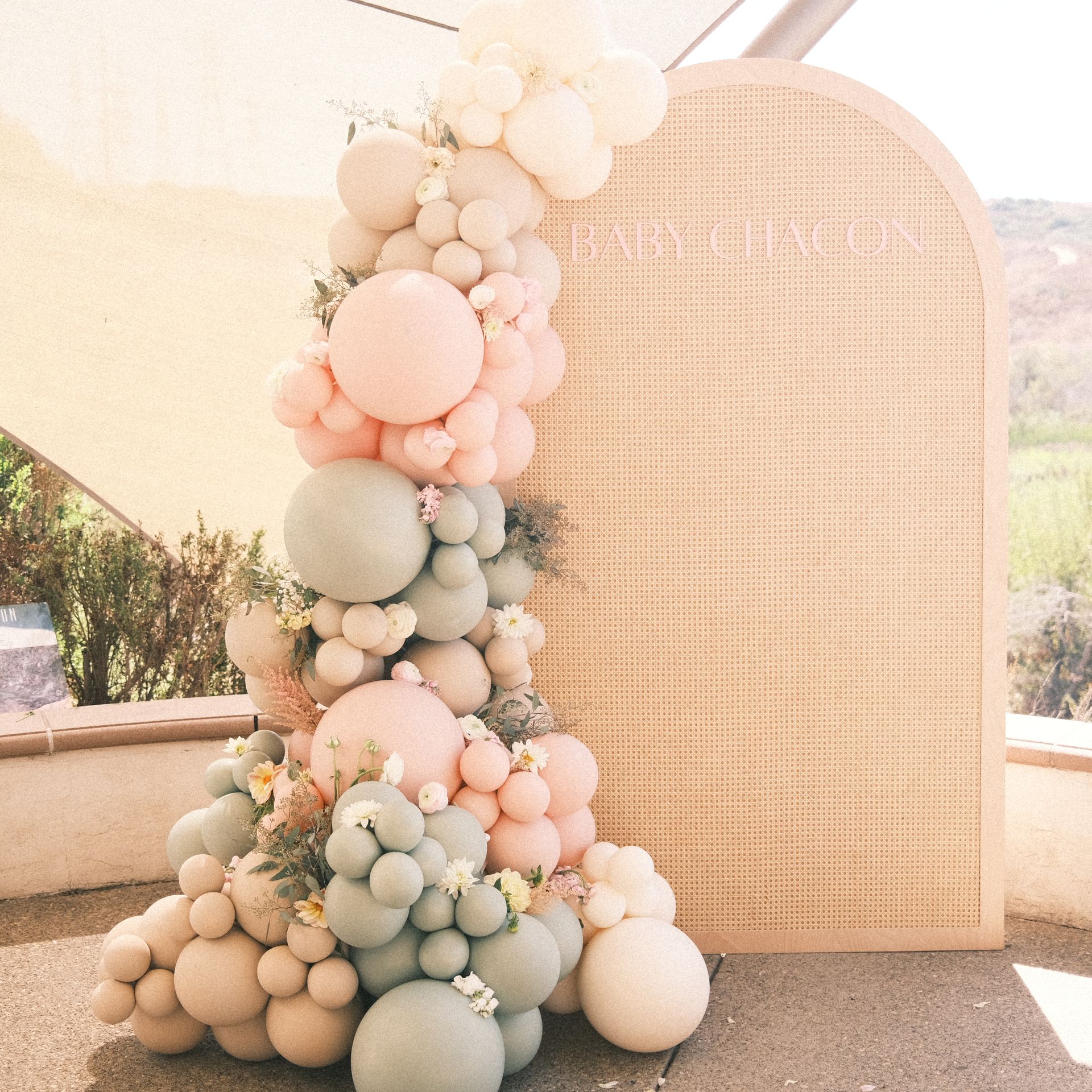Balloon garland in pastel colors next to a woven panel.