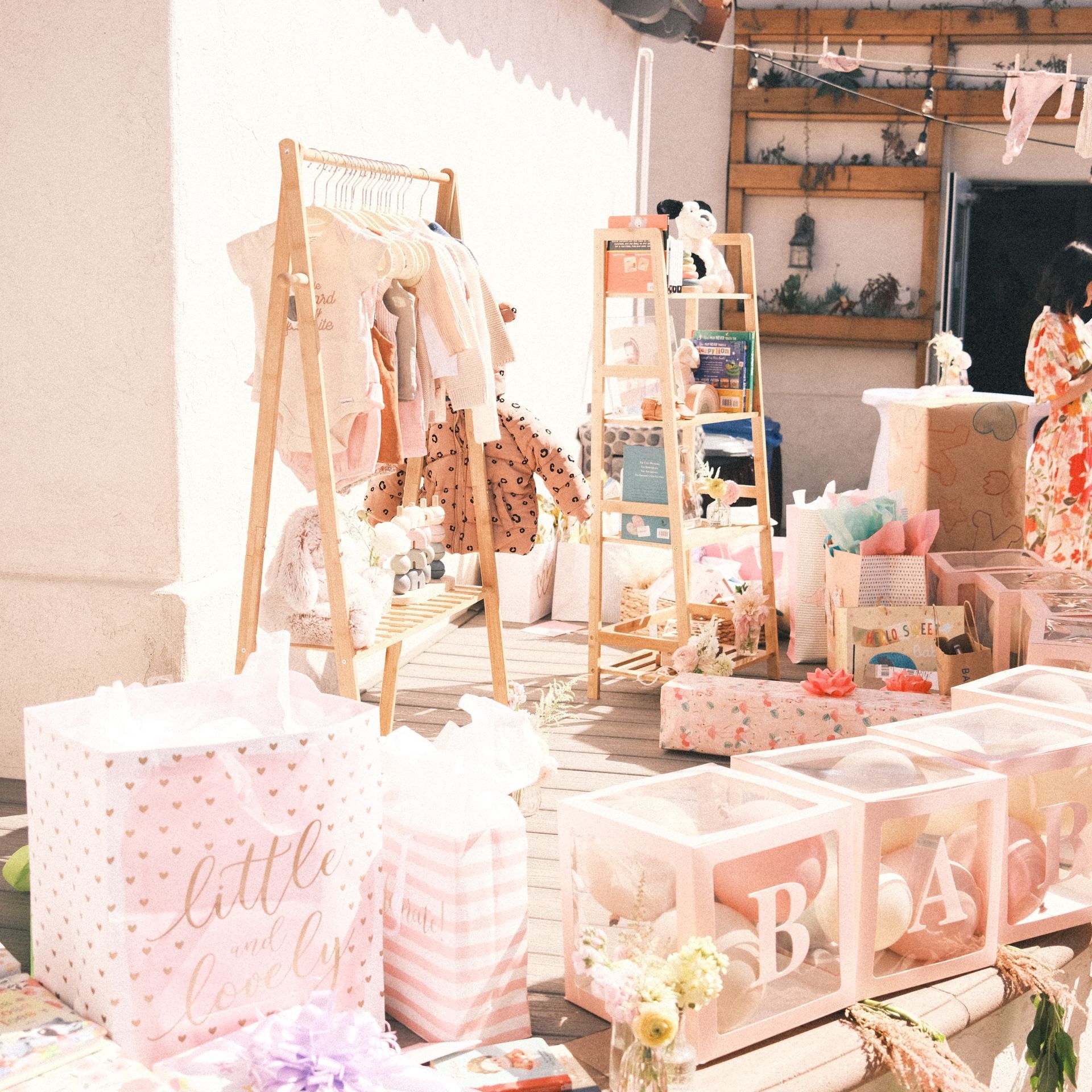 Baby shower decorations with clothing rack and gifts in pink and white.