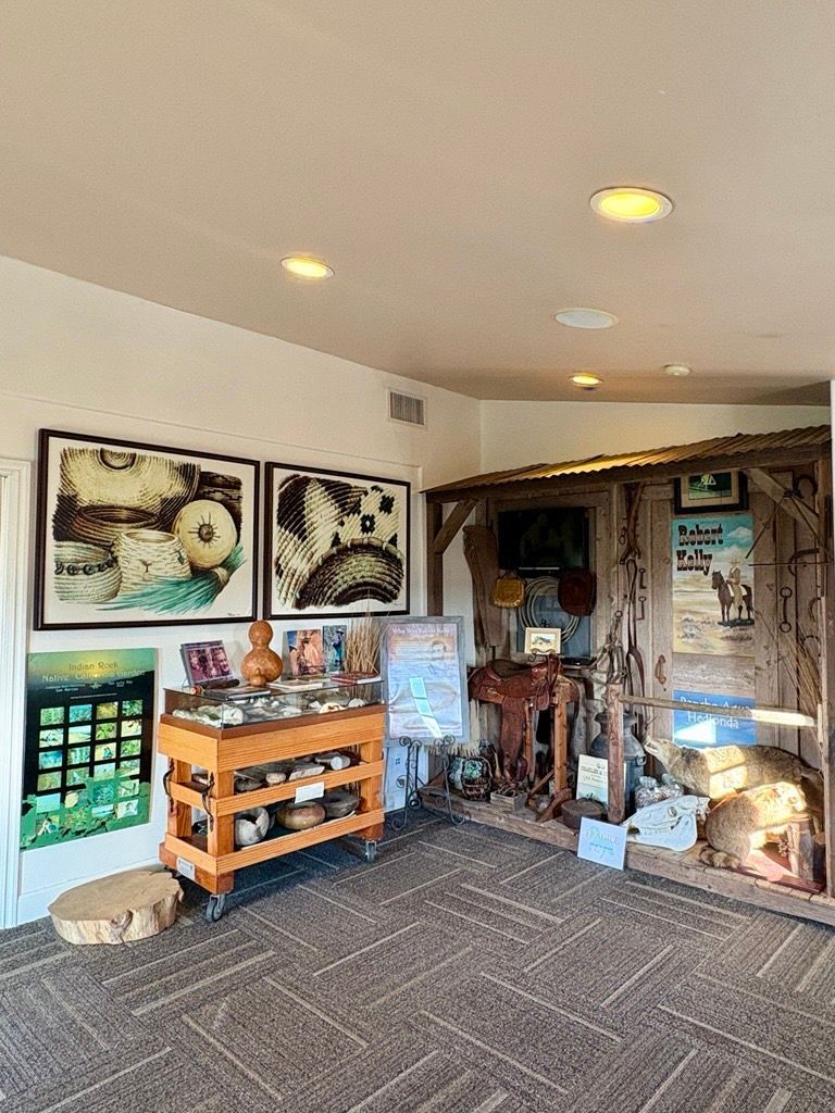 An exhibit room with display cases, artwork, and various artifacts related to a Western theme.