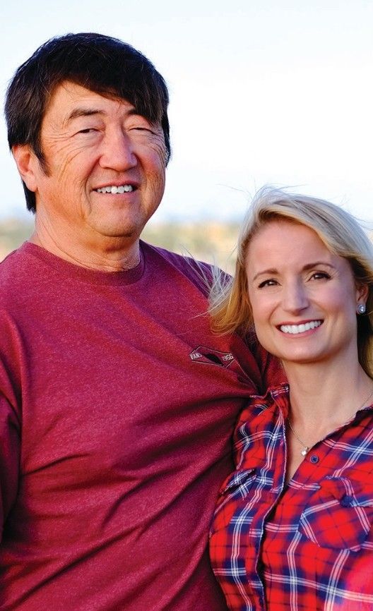 Man in maroon shirt smiles next to woman in red plaid.