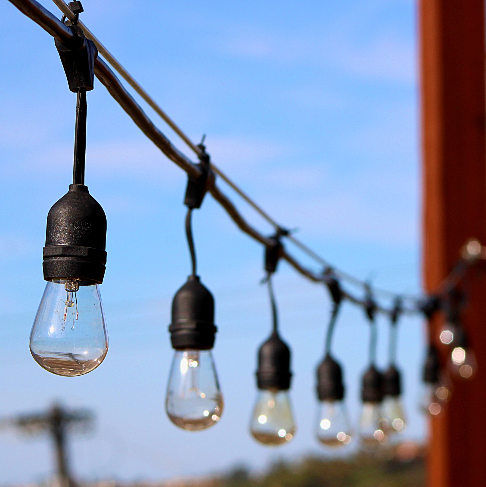 String lights with clear bulbs hang against a blue sky.