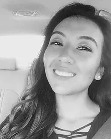 Woman smiling in car, long hair, wearing earrings.