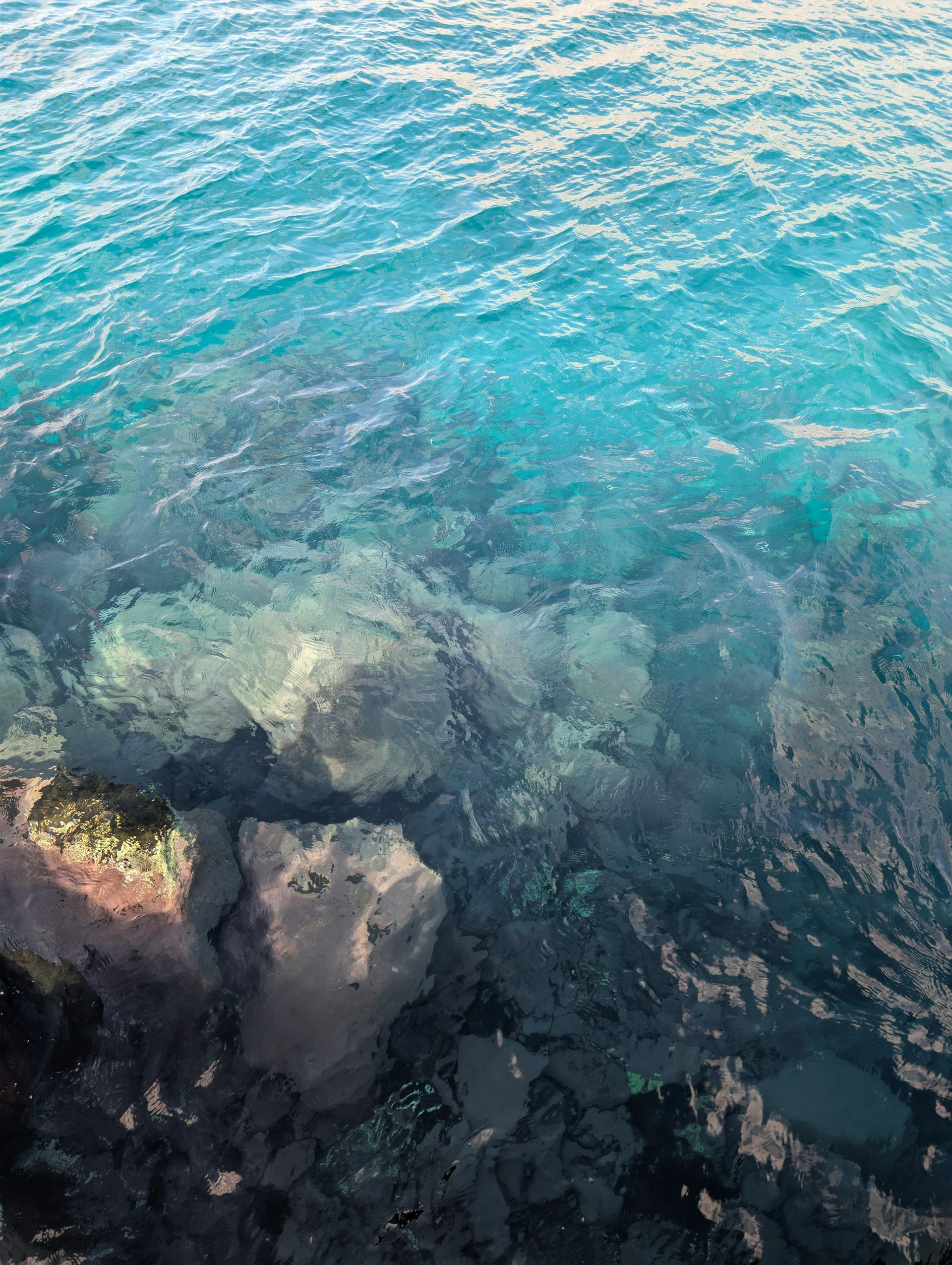 Clear turquoise water over submerged rocks.