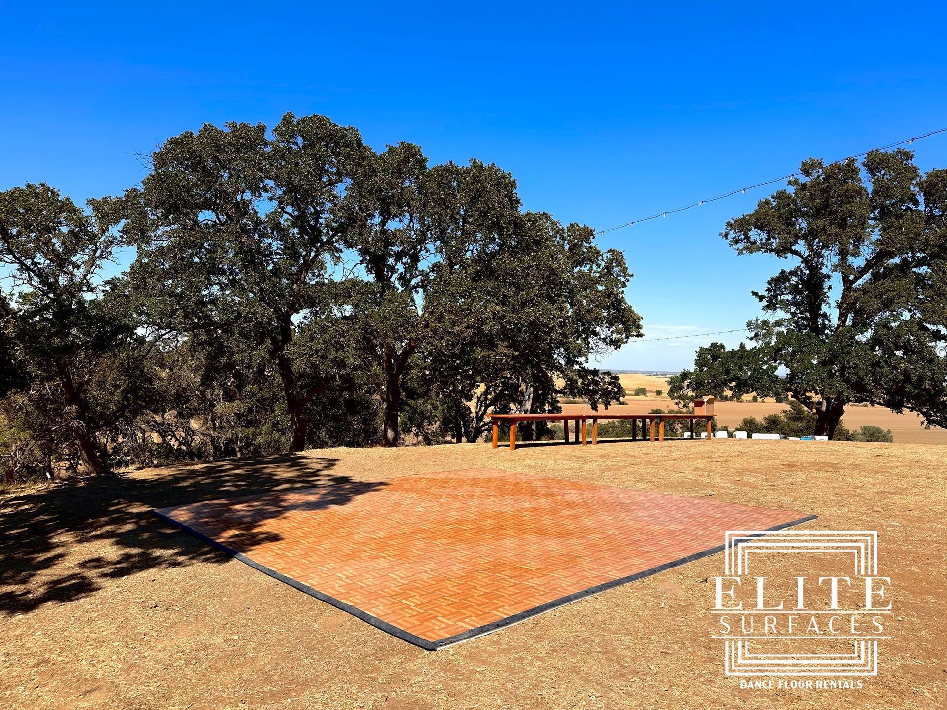 A dance floor in the middle of a field with trees in the background