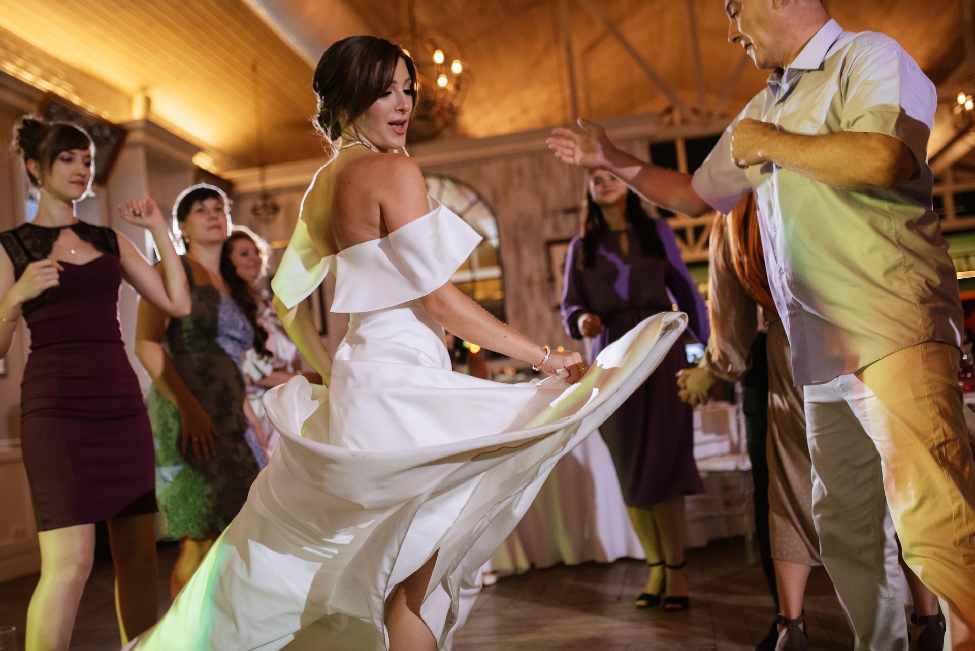 A bride and groom are dancing with their wedding guests at their wedding reception.