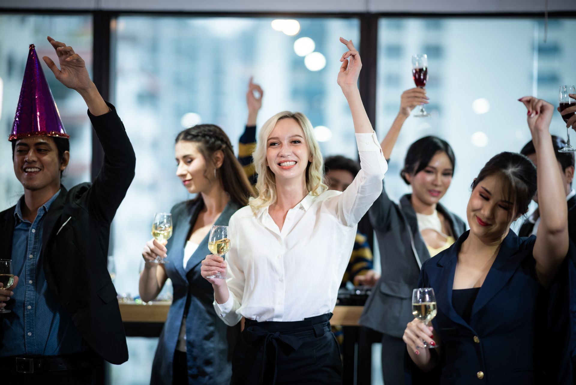 A group of people are holding champagne glasses and dancing at a party.