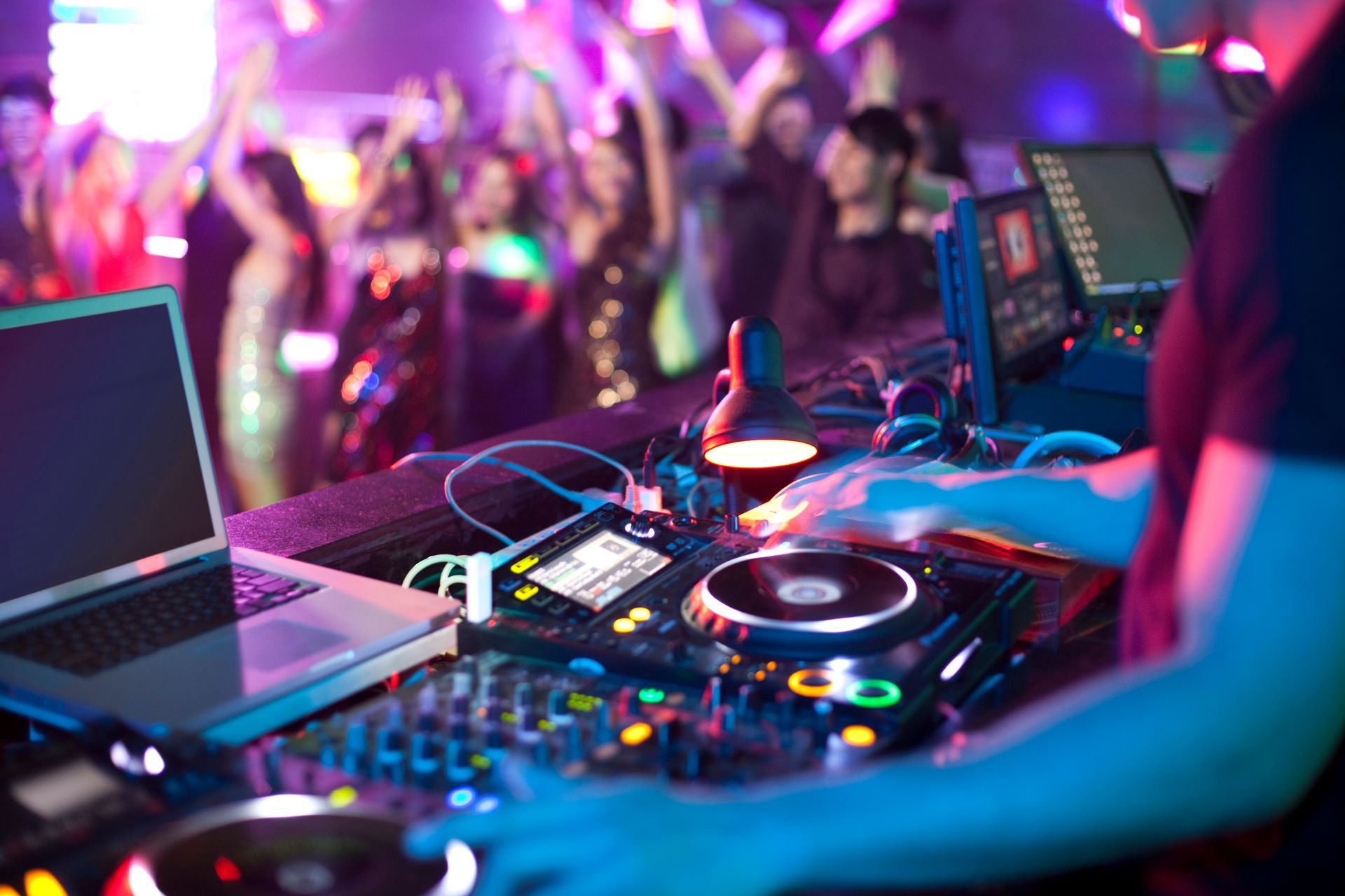 A dj is playing music at a party in front of a crowd.