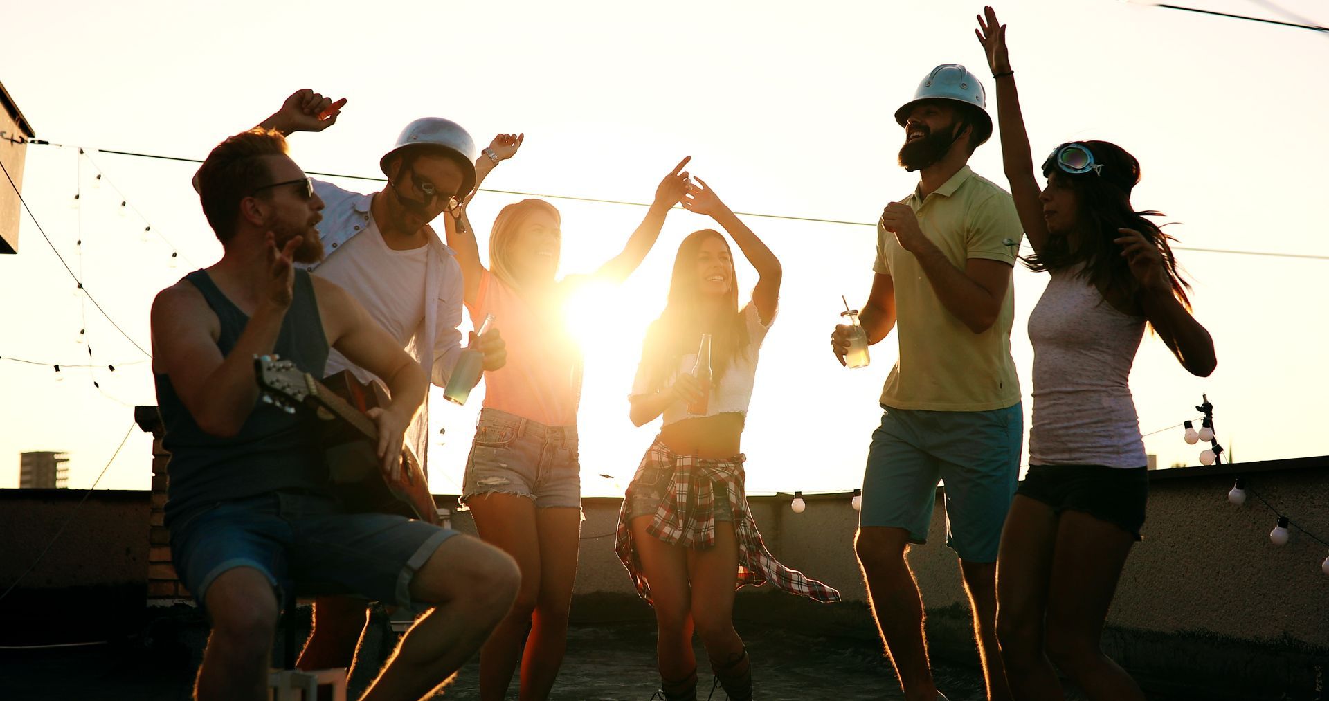 A group of young people are dancing on a rooftop party.