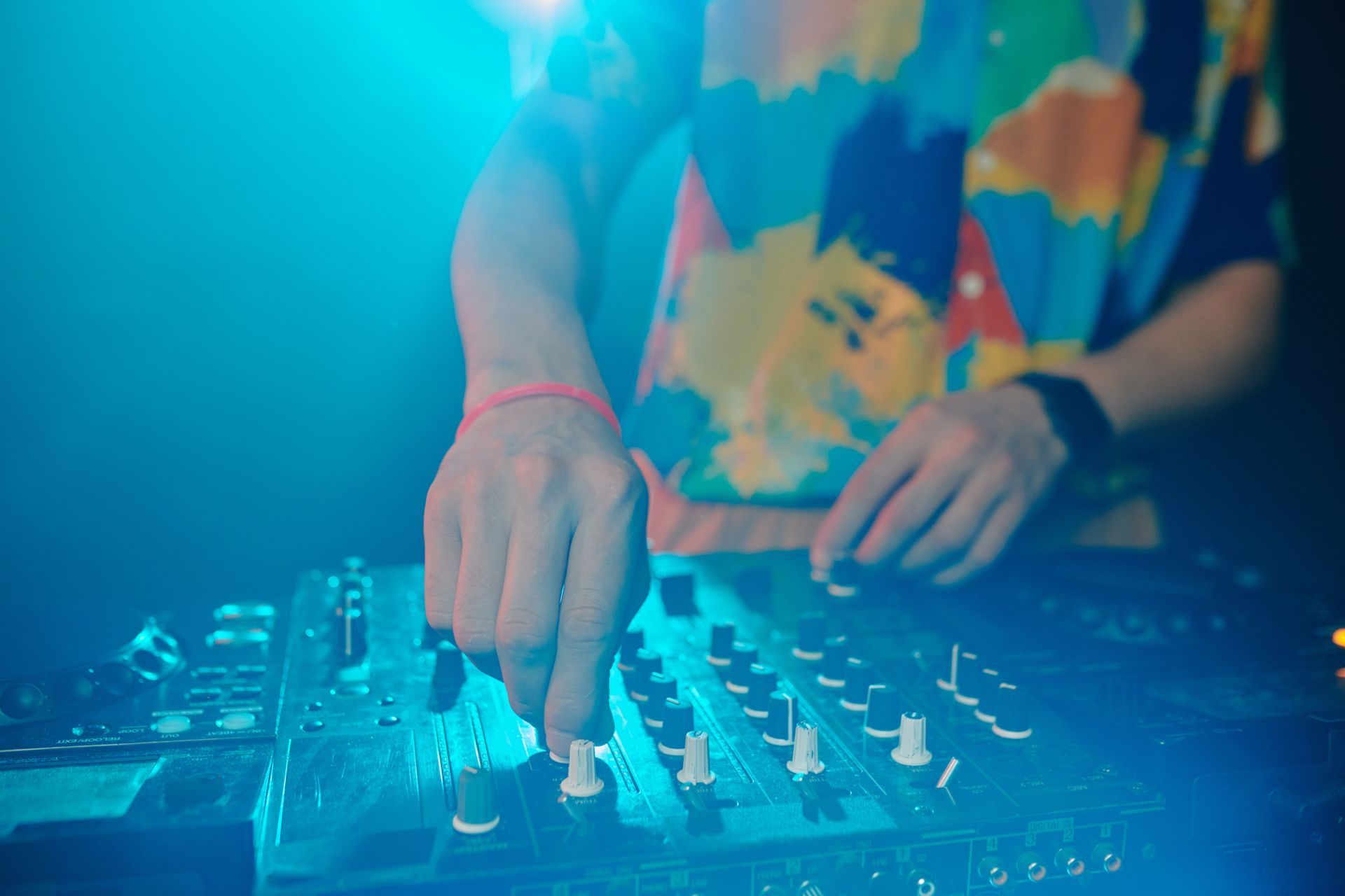 A dj is playing music on a mixer in a club.