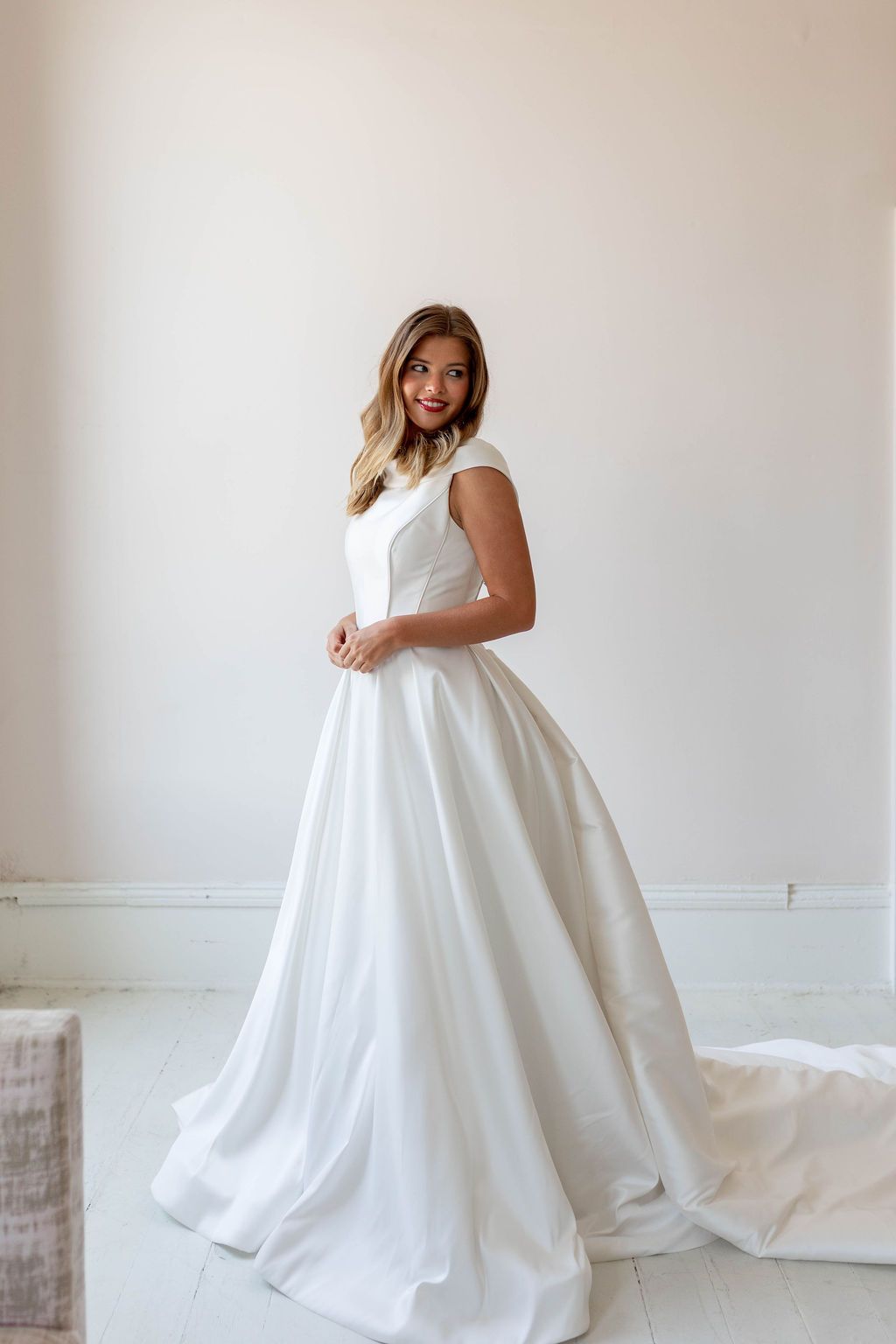 Woman in a white wedding gown standing in a bright, minimalist room