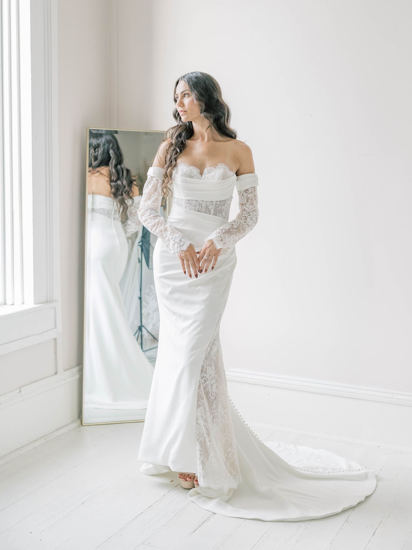 A woman in a white wedding dress is standing in a room.