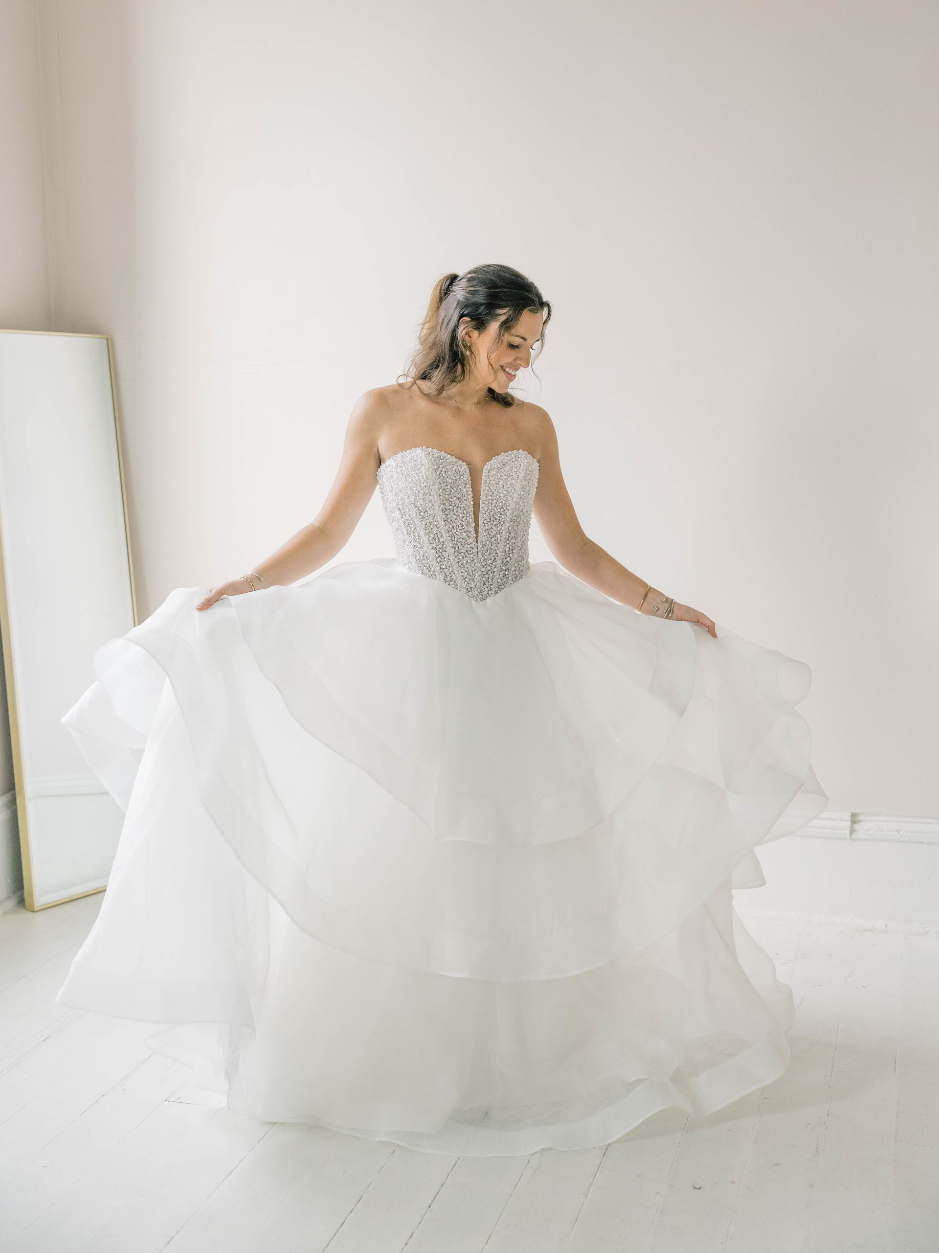A woman in a white lace wedding dress is standing in front of a door.