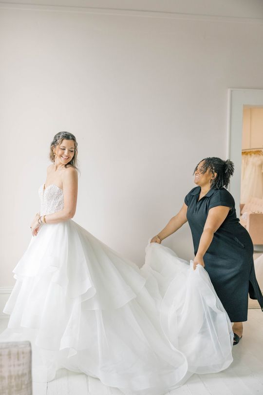 A woman in a white wedding dress is standing in front of a mirror.