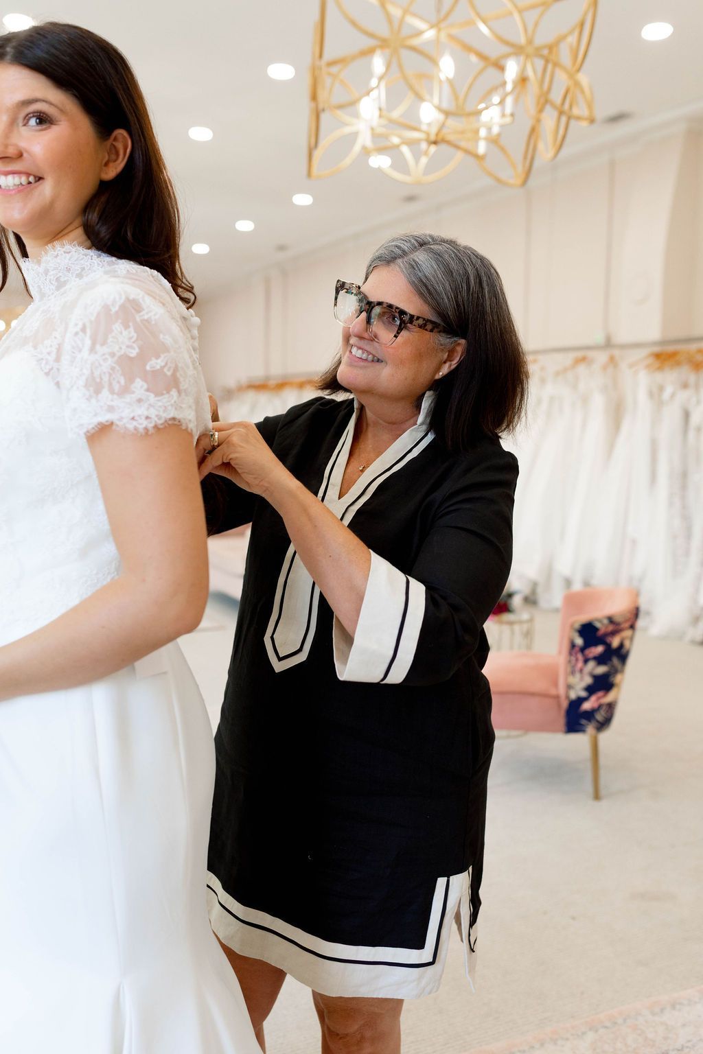 A woman is helping a woman in a wedding dress with her veil.