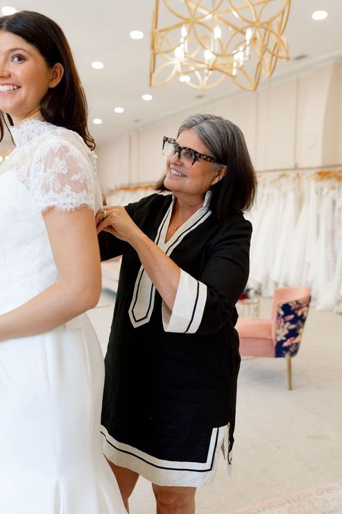 A woman is helping a woman in a wedding dress with her veil.