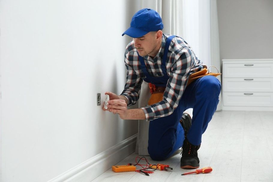 Electrician installing a hanging light fixture in a modern kitchen or dining area.