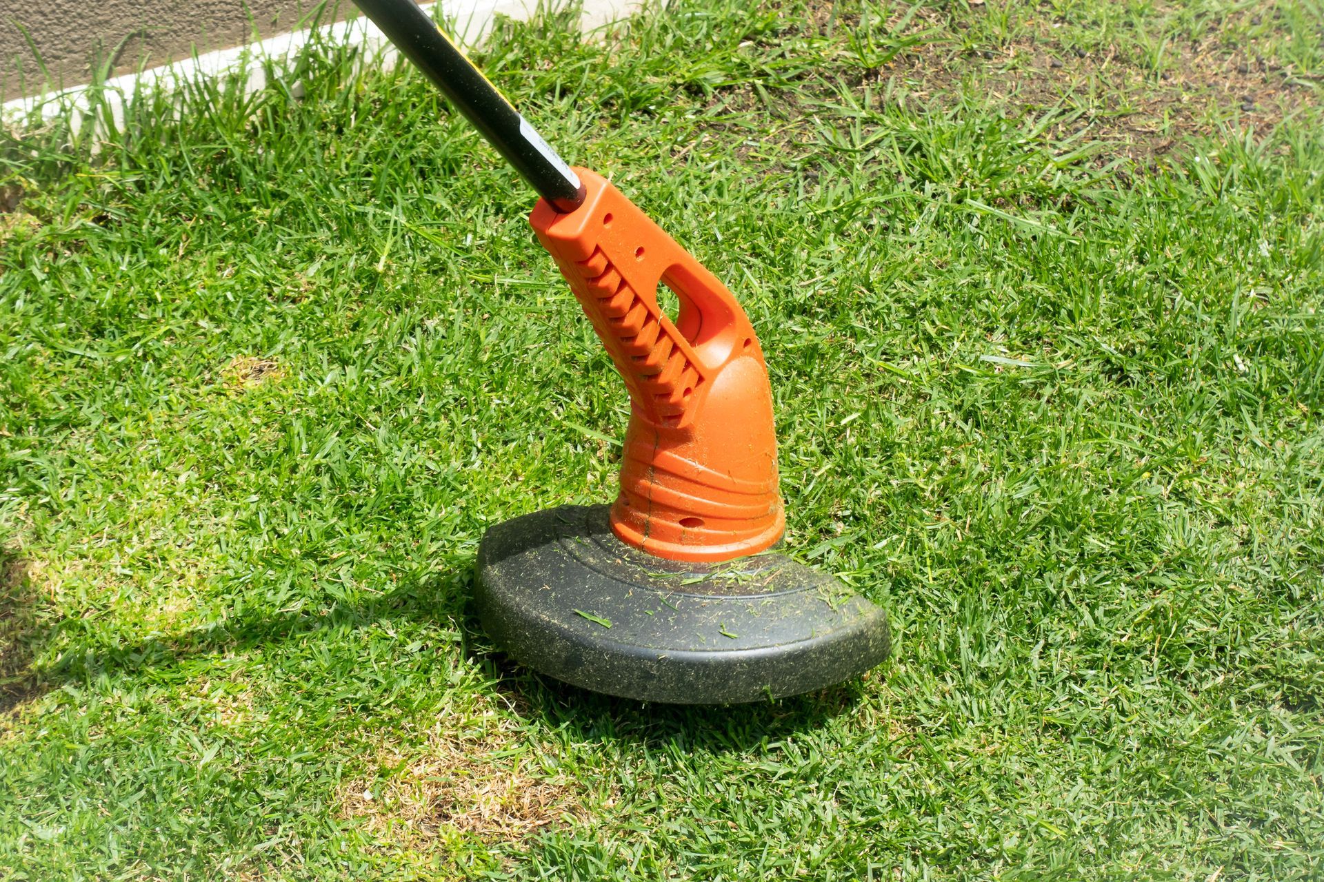 A orange lawn mower is sitting on top of a lush green lawn.
