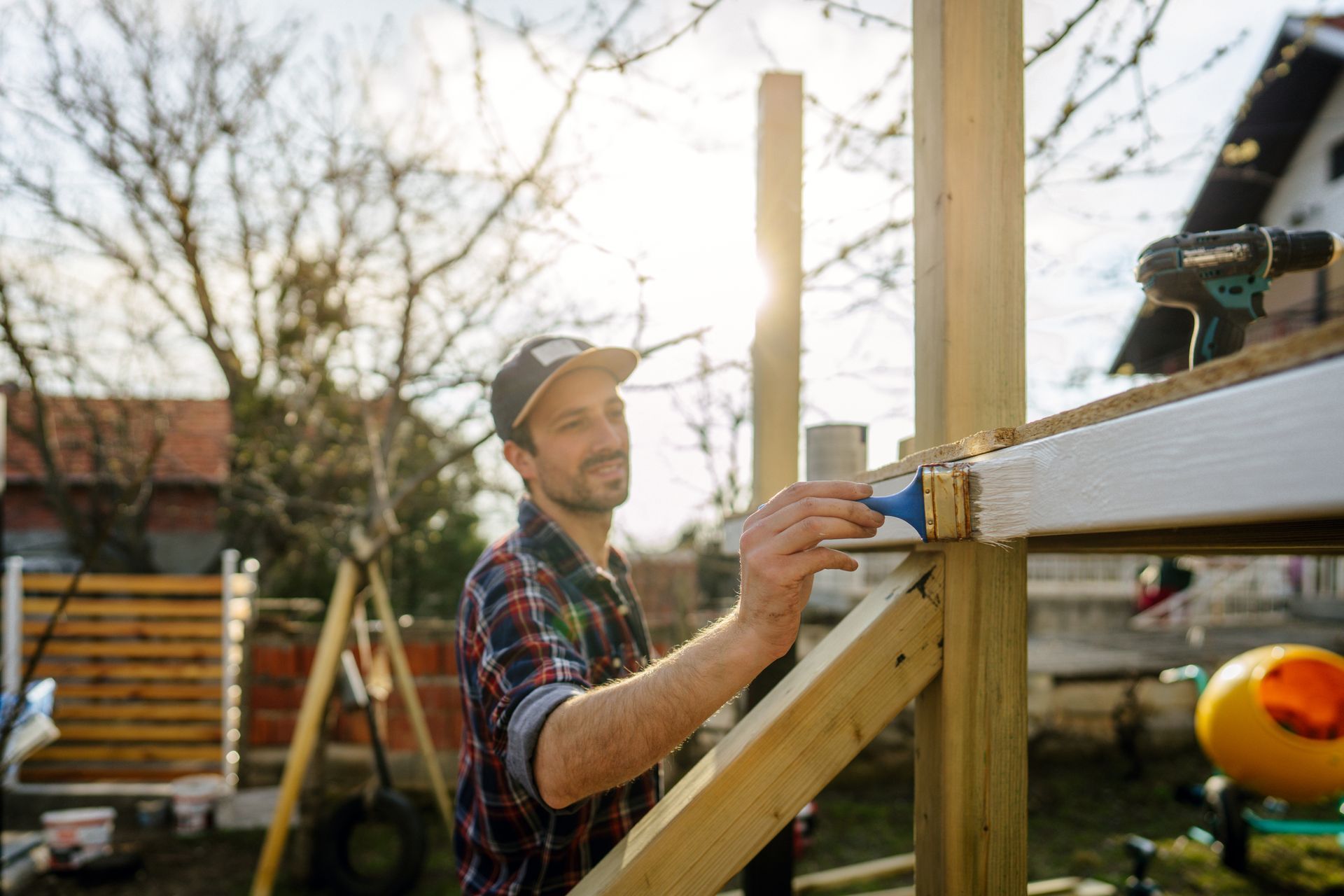 A man is painting a wooden structure with a brush.