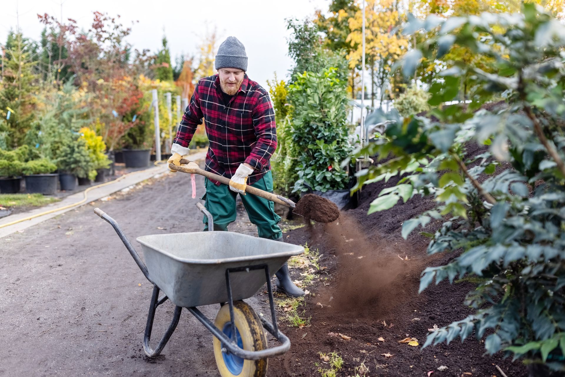 A man is pushing a wheelbarrow with dirt in it.