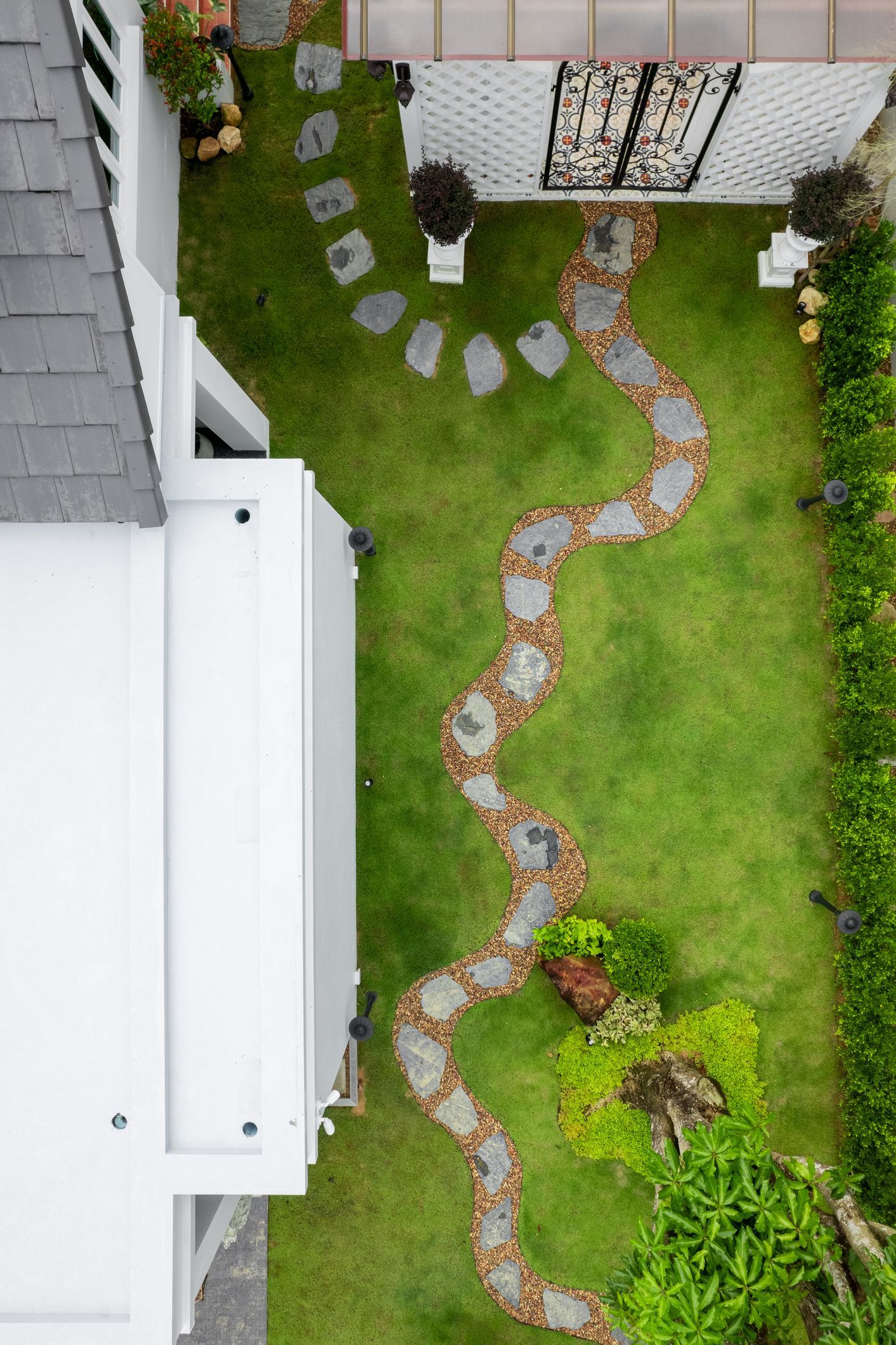 An aerial view of a garden with a stone path leading to a house.