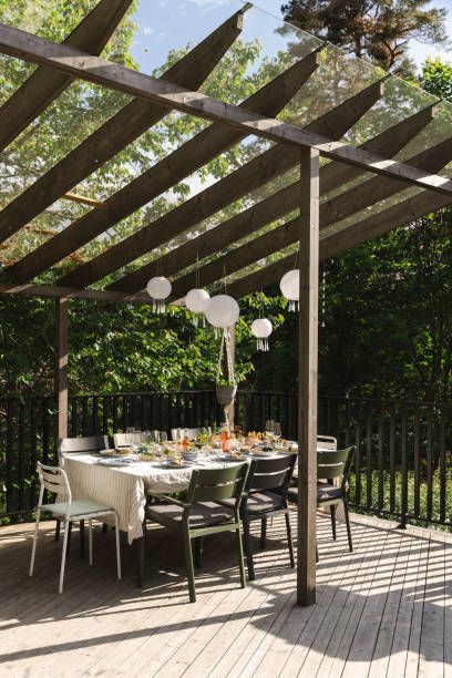 A wooden deck with a table and chairs under a pergola