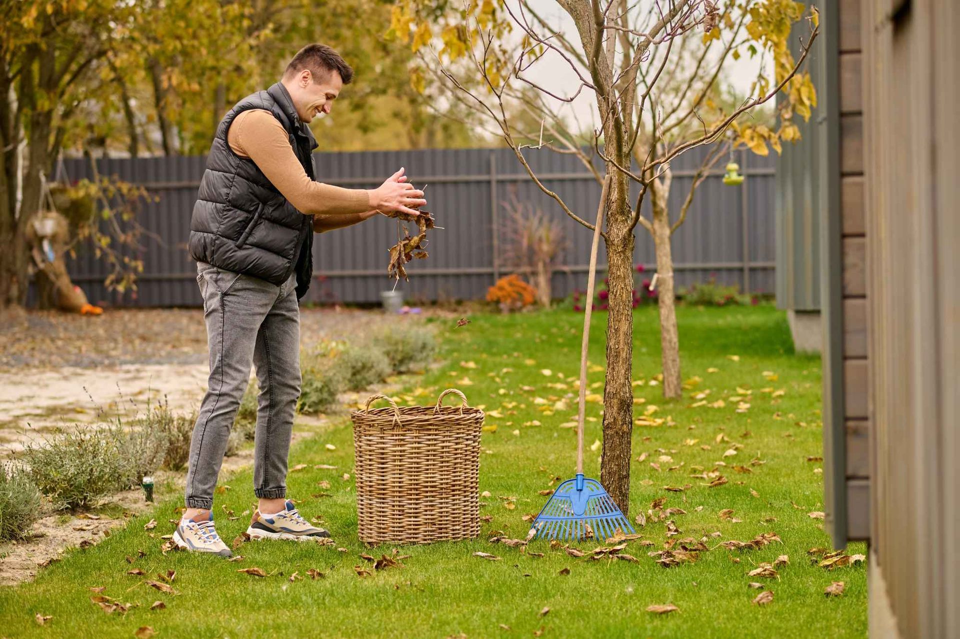 A man is standing next to a tree in a backyard.