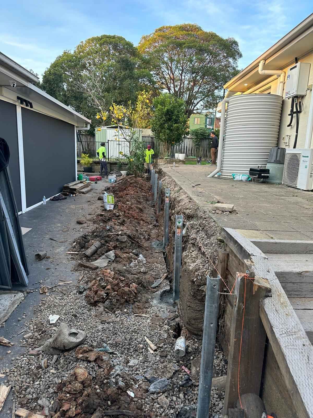A fence is being built in the backyard of a house.