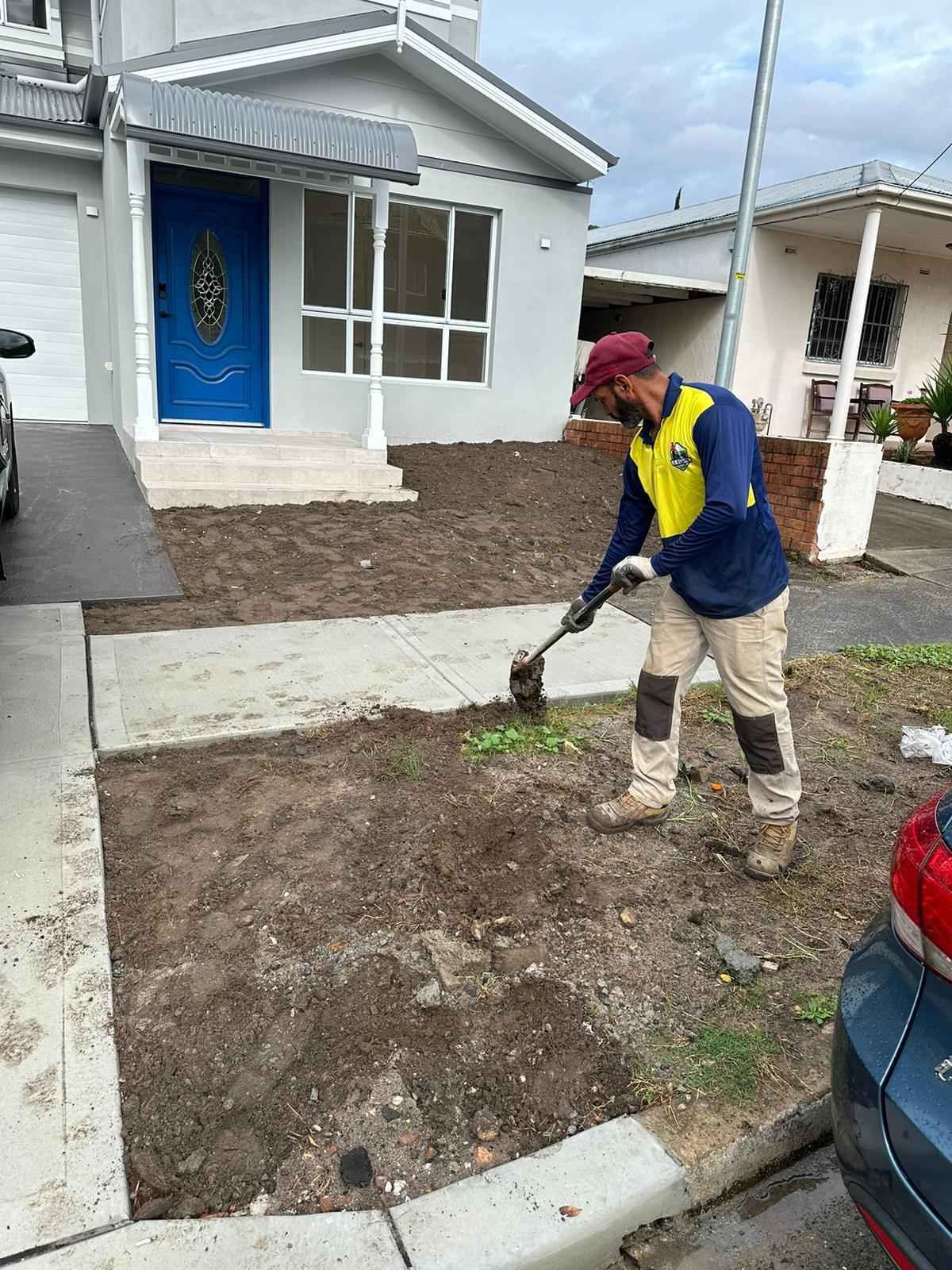 A man is digging in the dirt in front of a house.