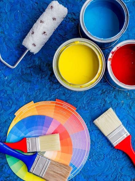 A bunch of paint cans and brushes on a blue surface.