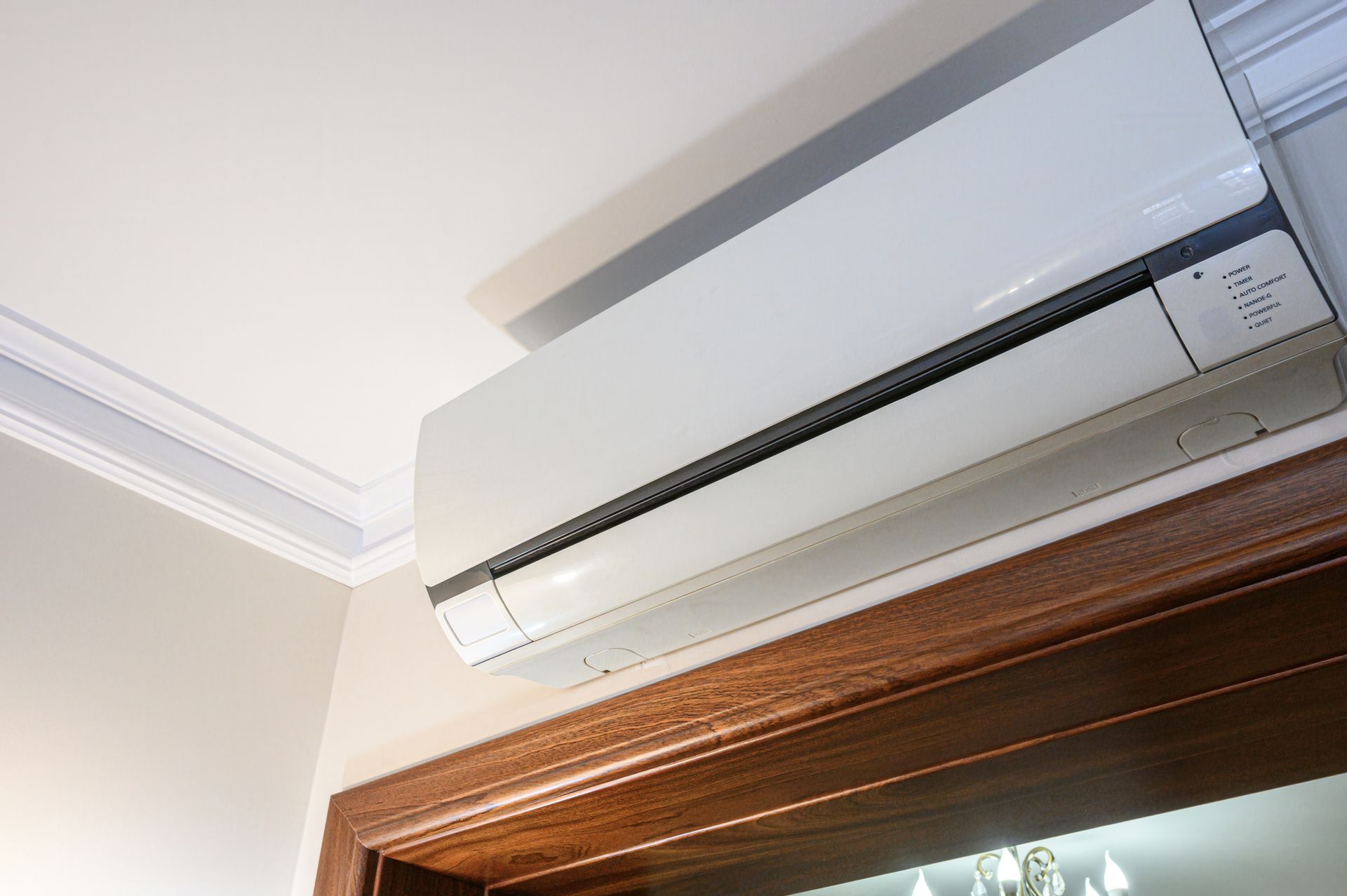 Wall-mounted white air conditioner above a wooden window frame