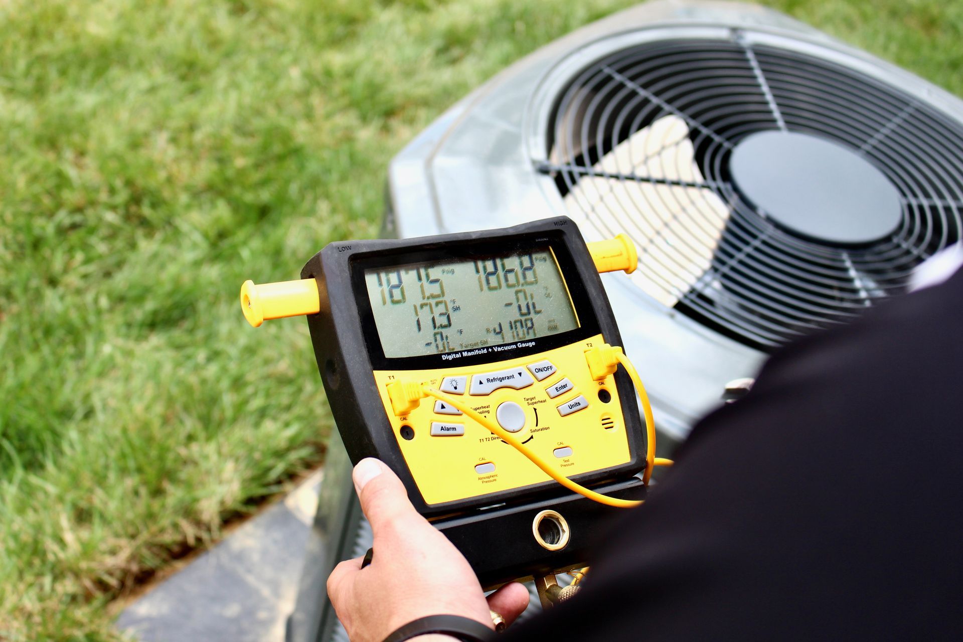 Technician using a digital meter to inspect an outdoor air conditioner unit