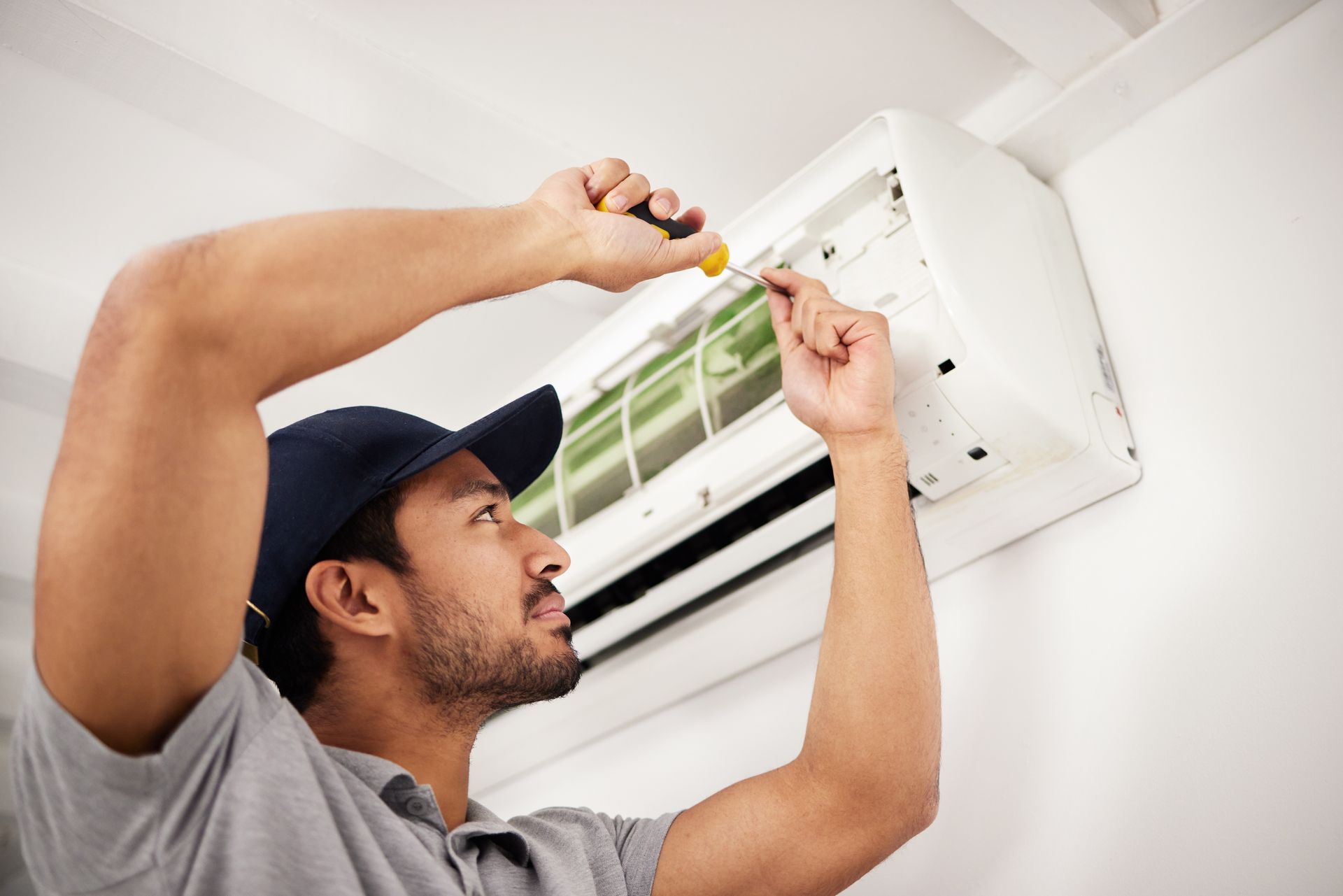 Technician repairing a wall-mounted air conditioning unit Technician repairing a wall-mounted air conditioning unit