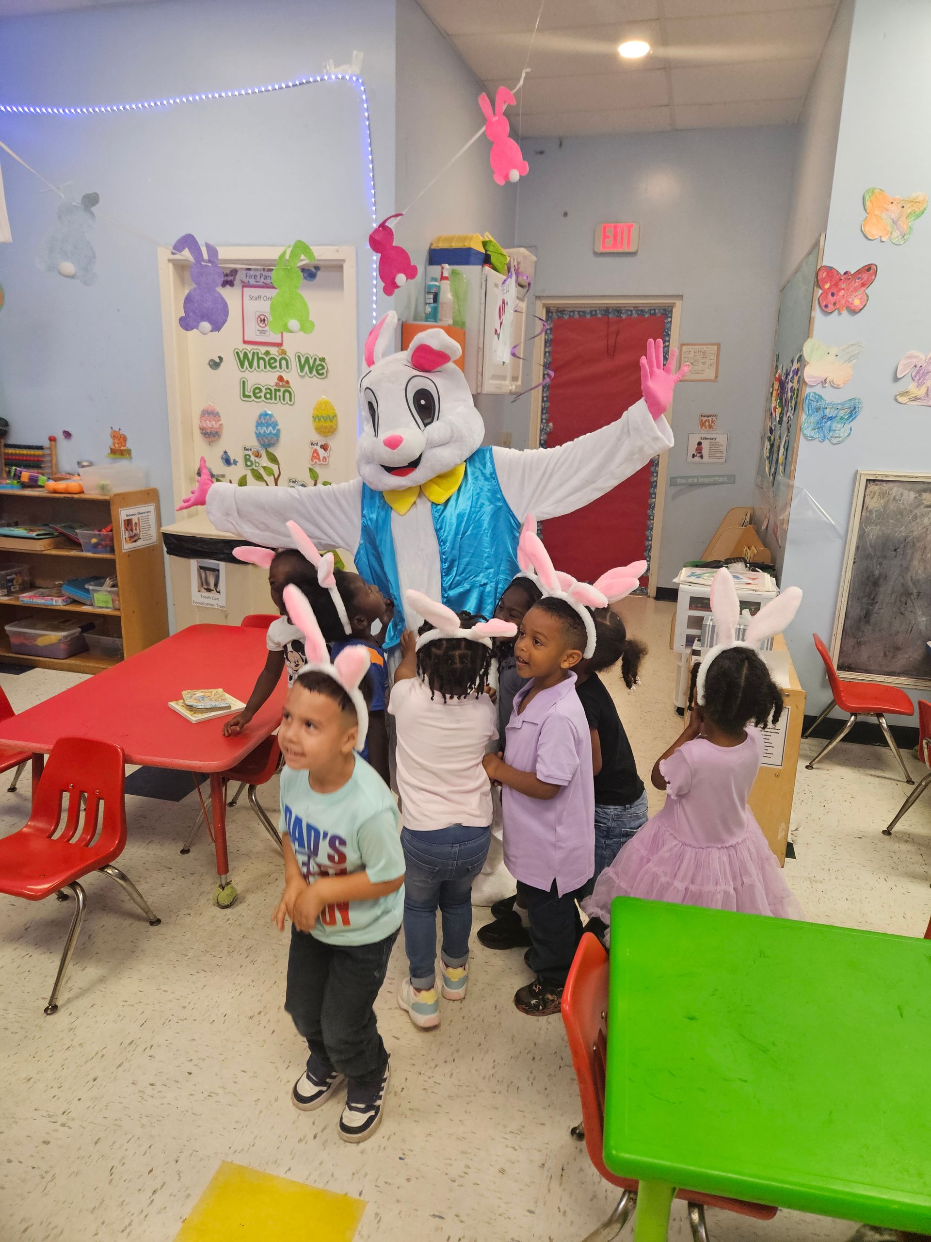 Children wearing bunny ears with the Easter Bunny in a classroom.