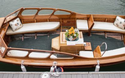 Wooden boat interior with white cushions and a small table topped with flowers
