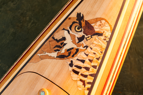 Wooden canoe deck with an orange and black painted design on water.