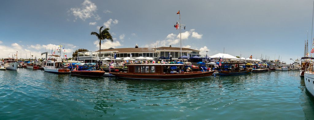 Crowded boat on blue water at a marina, with people on deck and flags flying