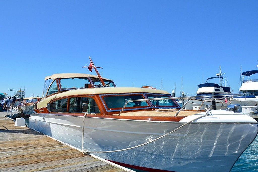 White and wood motor yacht docked at a marina under a clear blue sky
