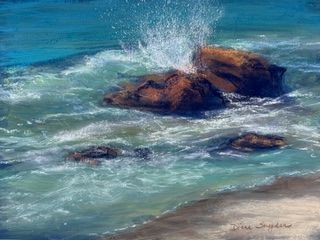 Waves splash over dark rocks in a blue-green ocean