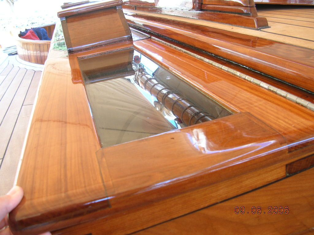 Wooden coffin with a glass viewing panel, shown in close-up indoors.