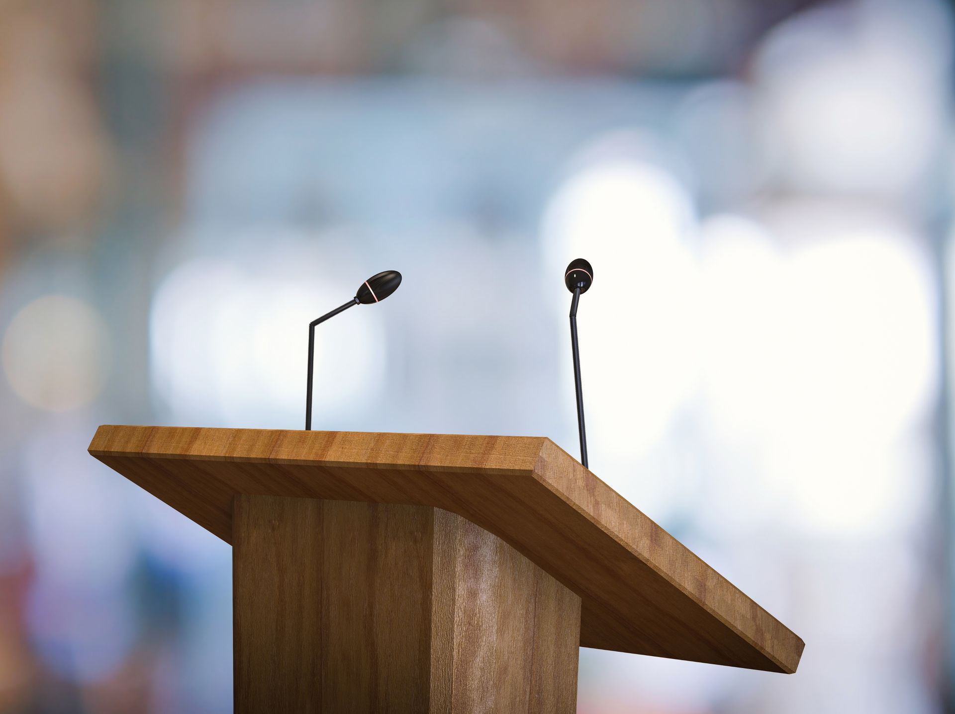Wooden podium with two microphones against a blurred background