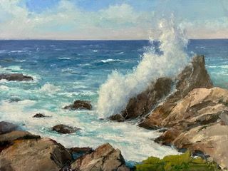 Waves crashing against rocky shoreline under a blue sky