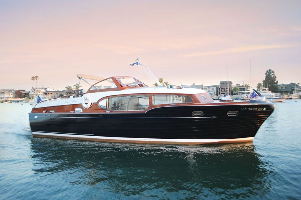 Luxury black and wood motor yacht cruising on calm water at sunset