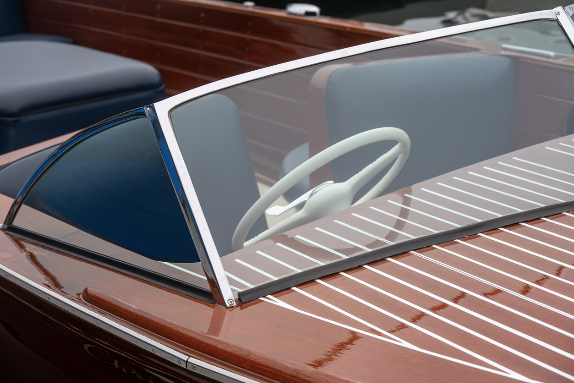 Close-up of a vintage brown car windshield and steering wheel with chrome trim and blue seats